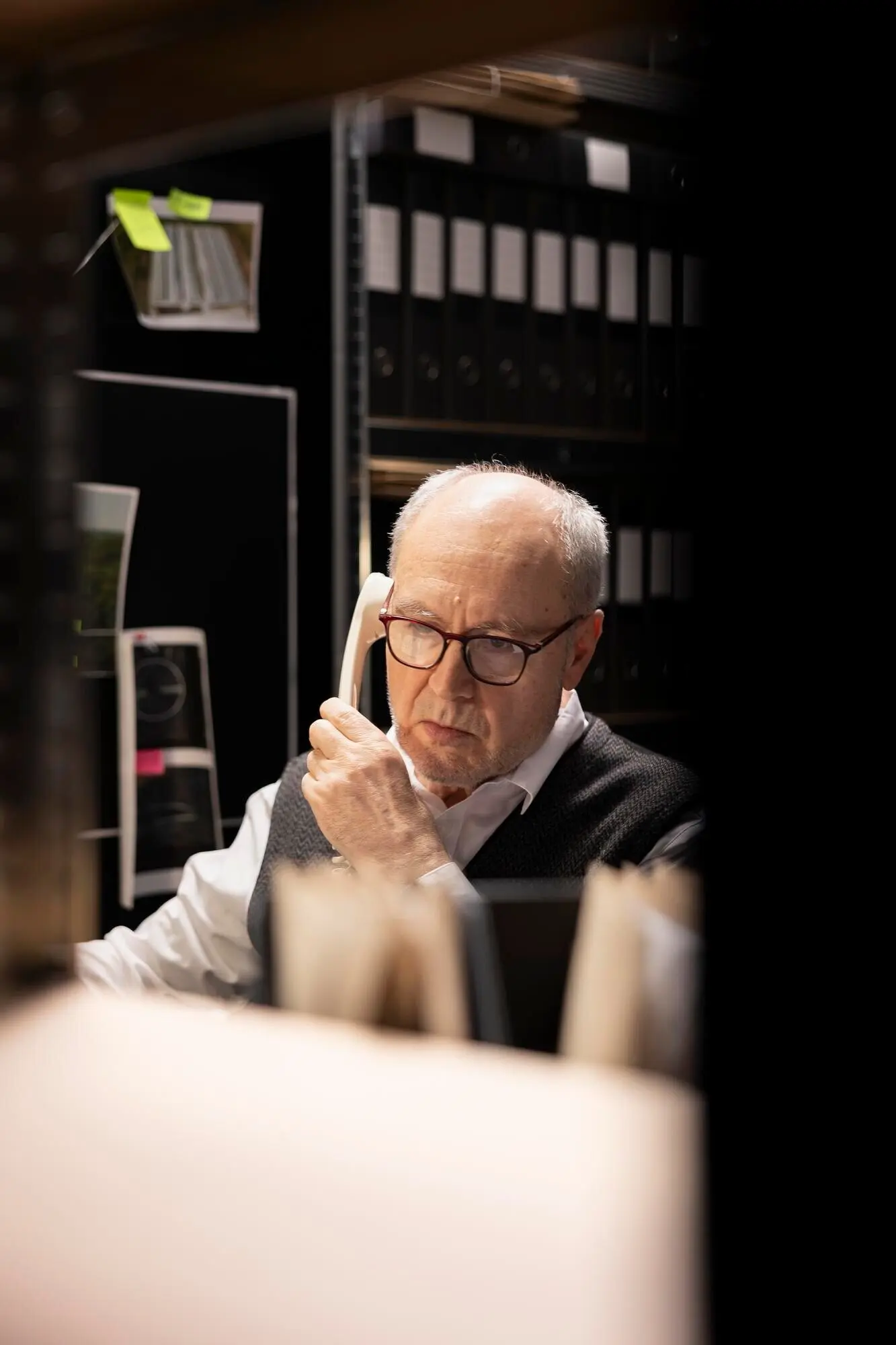 Inspector sénior verificando información para un caso criminal con un teléfono fijo y utilizando técnicas forenses.