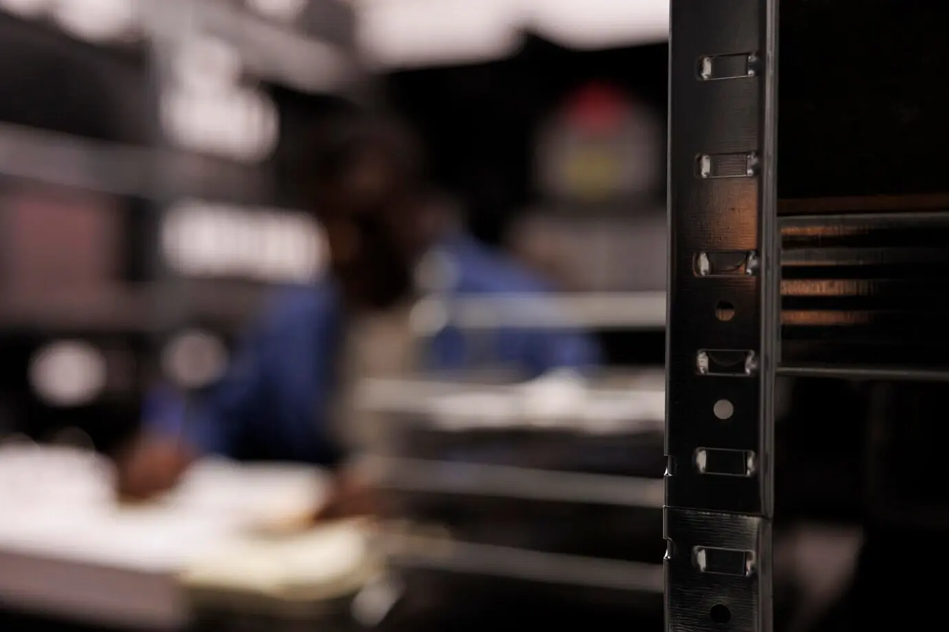 Enfoque selectivo en estanterías repletas de informes de criminología; al fondo, un detective analiza pruebas de la escena del crimen. Un inspector afroamericano trabaja en un caso de persona desaparecida en una sala de archivos.